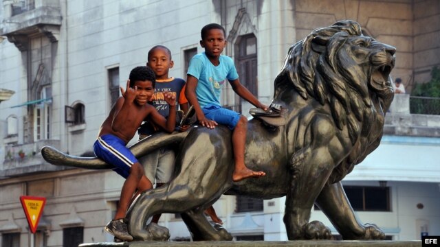 Varios niños juegan sobre uno de los leones del Paseo del Prado de La Habana (Cuba)