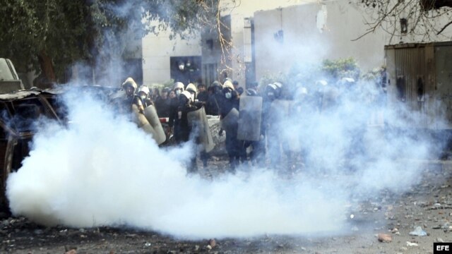  Agentes de policía antidisturbios egipcios, tratan de protegerse de los gases lacrimógenos lanzados por los manifestantes durante una protesta contra el "decretazo" del presidente egipcio, Mohamed Morsi. 