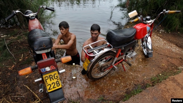 Un grupo de jóvenes lavan sus motocicleetas en el Río Guanímar.