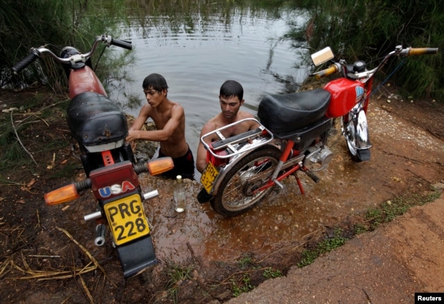 Un grupo de jóvenes lavan sus motocicletas en el Río Guanímar.