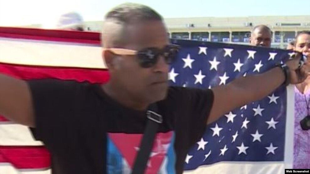Daniel Llorente sostiene la bandera estadounidense mientras espera la llegada del crucero Adonia.