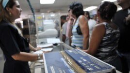 Empleada de una tienda de La Habana vende un reproductor de DVD