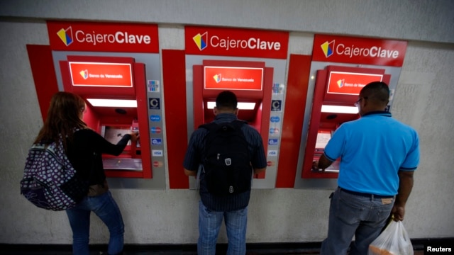 Personas extrayendo su dinero hoy en Caracas de los cajeros automáticos tras el anuncio del Gobierno de la devaluación del bolívar