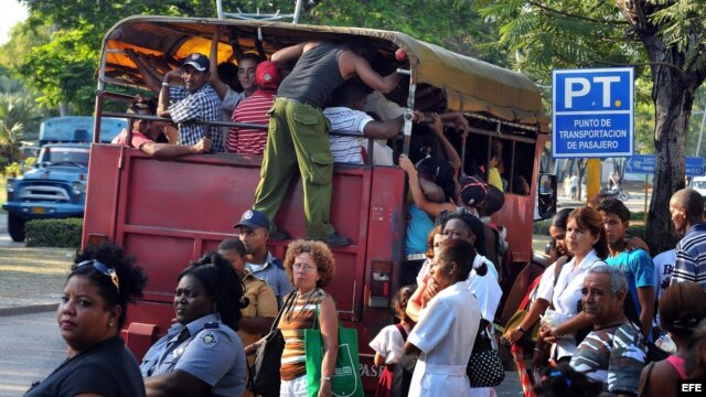 Varias personas suben a un camión de transporte de pasajeros en Santiago de Cuba.