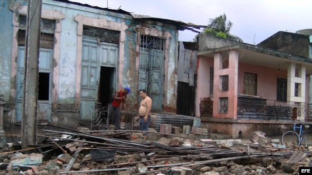 Dos hombres limpian escombros en una casa que ha sido parcialmente destruida por el paso del huracán "Sandy", en la ciudad de Guantánamo (Cuba). 