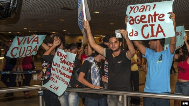 BRA509. RECIFE (BRASIL), 18/02/2013.- Manifestantes que rechazan la visita al país de la disidente cubana Yoani Sánchez, sostienen carteles hoy, lunes 18 de febrero de 2013, en el aeropuerto internacional Guararapes, de la ciudad de Recife (nordeste de Br