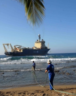 Obreros cubanos arrastran el cable submarino de fibra óptica en la playa de Siboney, en Santiago de Cuba.