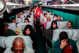 Cubanos en tránsito hacia EE.UU. son trasladados en un autobús a la salida del Aeropuerto Internacional Monseñor Oscar Arnulfo Romero.
