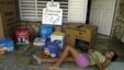 ARCHIVO.  Una joven descansa en el portal de su casa que donde se muestran algunas cajas de los efectos electrodomésticos de la llamada "revolución energética" en Cuba. 