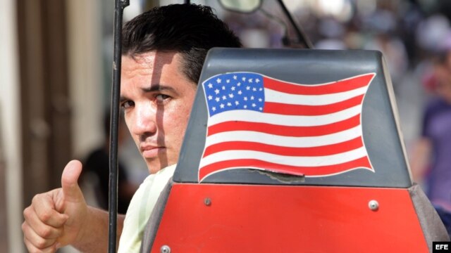 Un hombre saluda desde una bicitaxi con la bandera de EEUU.
