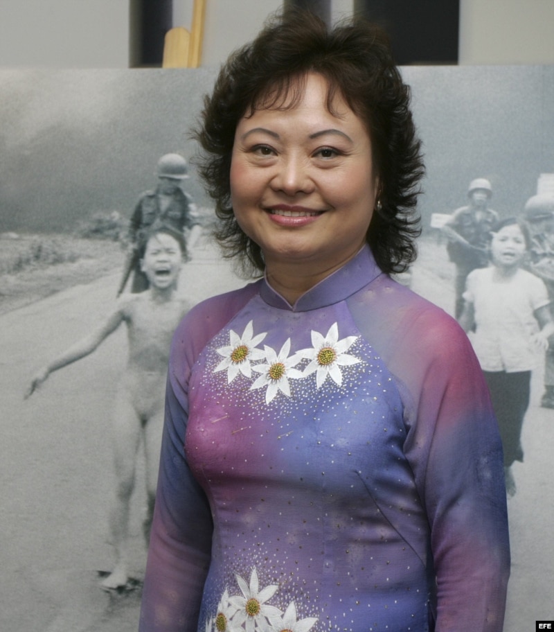 Kim Phuc posa junto a la famosa fotografia de la guerra de Vietnam que ella protagonizó.