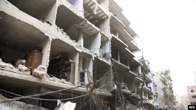 Fotografía de archivo cedida por la agencia de noticias SANA que muestra a unos ciudadanos sirios en el lugar donde se registró la explosión de un coche bomba en el barrio de Def al Shuk en Damasco, Siria. 