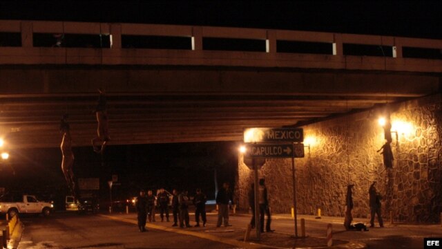 Los cuerpos de cuatro jóvenes decapitados se observan atados y colgando de un puente hoy, domingo 22 de agosto de 2010, en la autopista México-Acapulco.