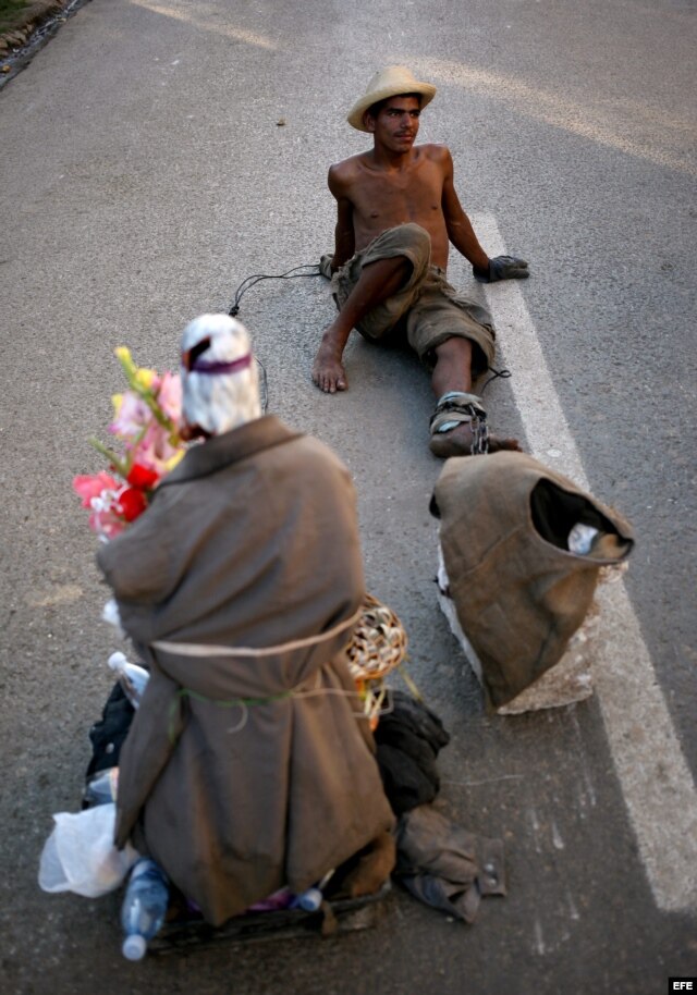 Un hombre toma un descanso mientras arrastra una piedra y una imagen de San Lázaro el domingo 16 de diciembre de 2012, durante una procesión en el Santuario de El Rincón, Cuba.