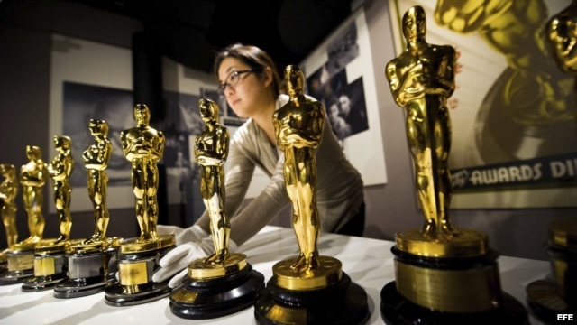 Una mujer coloca los premios de la academia de cine estadounidense.