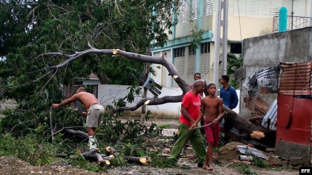 Varias personas talan árboles derribados por el huracán Sandy en el poblado de Caimanera, en la provincia de Guantánamo (Cuba). 