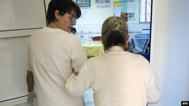 Una auxiliar acompaña a una enferma de alzheimer en el centro de día "La Pineda" en Castellón, España
