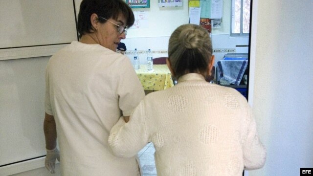 Una auxiliar acompaña al comedor a una enferma de alzheimer en el centro de día "La Pineda" en Castellón.  