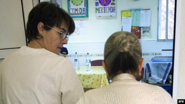 Una auxiliar acompaña al comedor a una enferma de alzheimer en el centro de día "La Pineda" en Castellón. 