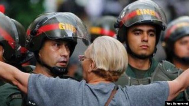 Una mujer venezolana trata de impedir el avance de agentes de la Guardia Nacional Bolivariana.
