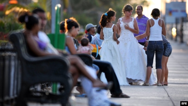 Una joven es ayudada por sus familiares a acomodar su vestido de quinceañera antes de posar para el fotógrafo en la Habana.