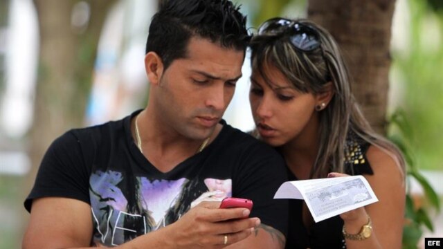  Dos jóvenes usan un teléfono móvil hoy, miércoles 9 de abril de 2014, en La Habana (Cuba)