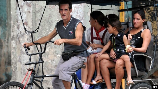 Dos mujeres viajan con sus hijas en un bicitaxi.
