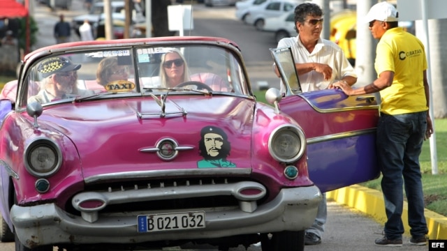 Un grupo de turistas pasea en un auto clásico con una pegatina de Ernesto Guevara. EFE