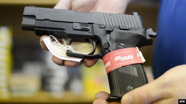 Un propietario de una armería muestra una pistola semiautomática Sig Sauer en su negocio.