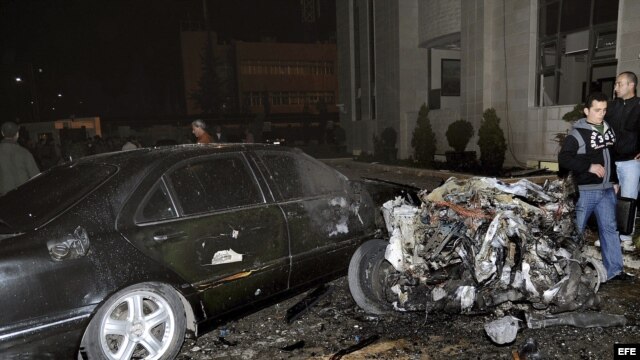 Fotografía cedida facilitada por la agencia siria de noticias SANA que muestra a unos policías sirios inspeccionando el lugar donde se ha registrado un atentado con coche bomba ante la sede del Ministerio del Interior sirio en Damasco, Siria. 