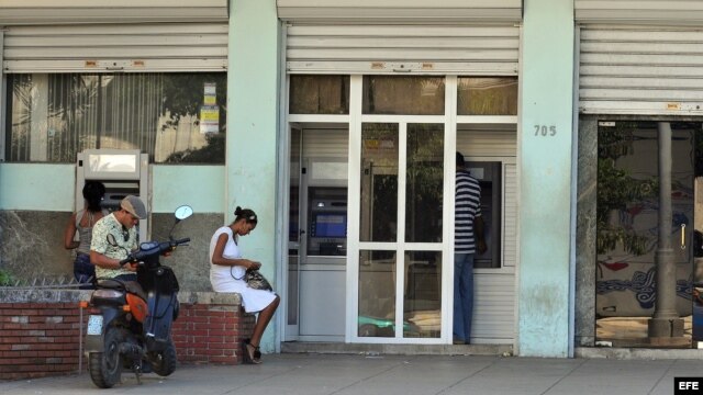 Ciudadanos sacan dinero en los cajeros automáticos de un banco.