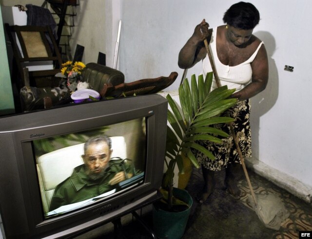 Archivo. Una mujer cubana limpia su casa mientras sigue por la TV la intervención especial de Fidel Castro.