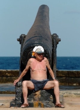 Un turista toma el sol en La Habana junto a un viejo cañón. EFE