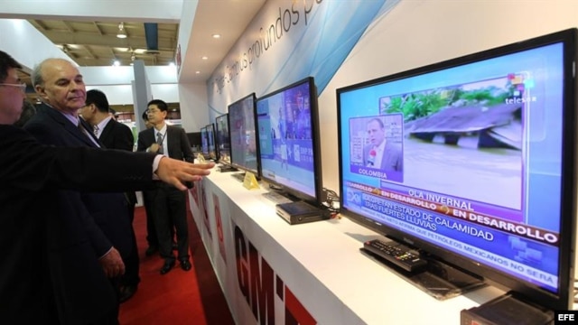 Varias personas observan una emisión de televisión digital en el stand de una compañía china que participa en la XV Convención y Feria Internacional Informática 2013.