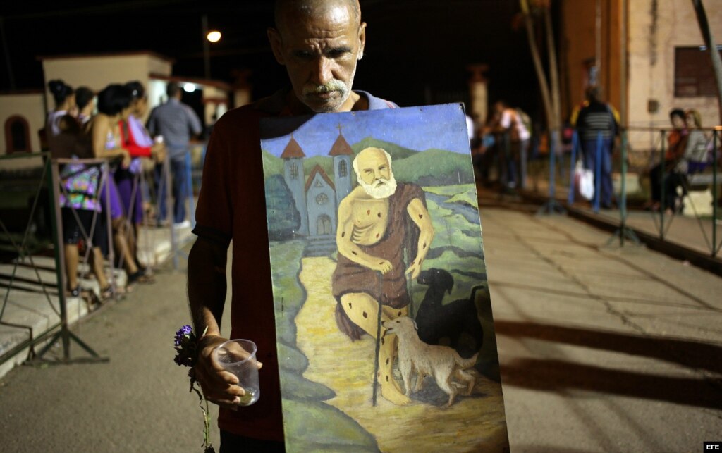 Un hombre camina con un cuadro con la imagen de San Lázaro el domingo 16 de diciembre de 2012, durante una procesión en el Santuario de El Rincón, Cuba. 