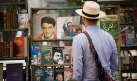 Un turista revisa viejos libros revolucionarios ofrecidos por un cuentapropista.