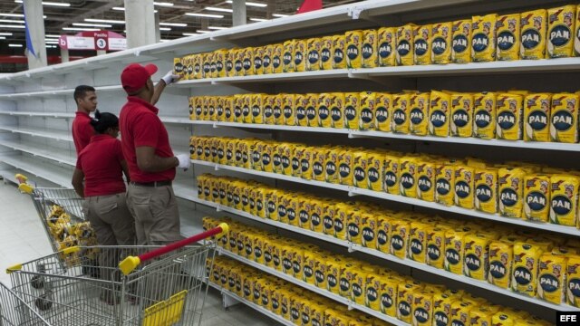 Trabajadores de un supermercado perteneciente a la red pública de alimentación del Gobierno reponen los productos en una estantería.