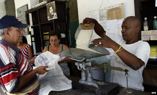Un bodeguero despacha a un anciano los productos que se distribuyen mediante la libreta de racionamiento en Cuba.