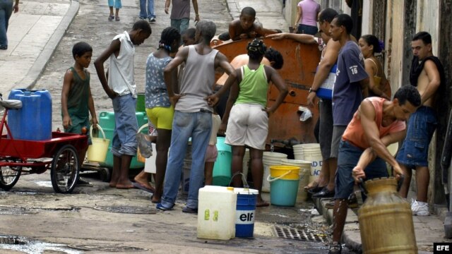 Varias personas esperan su turno para abastecerse del agua depositada en un tanque.