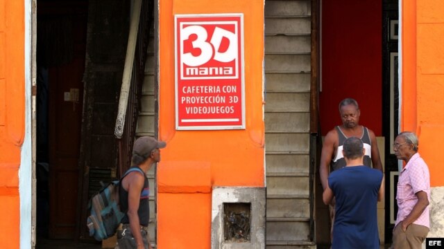 Varios hombres conversan en la puerta de un cine 3D de propiedad privada en La Habana (Cuba).