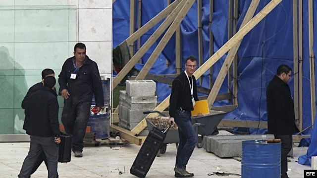  Un hombre (2º dcha), que pudiera ser uno de los investigadores internacionales, carga con una maleta en el mausoleo de Yaser Arafat en Ramala (Cisjordania).  