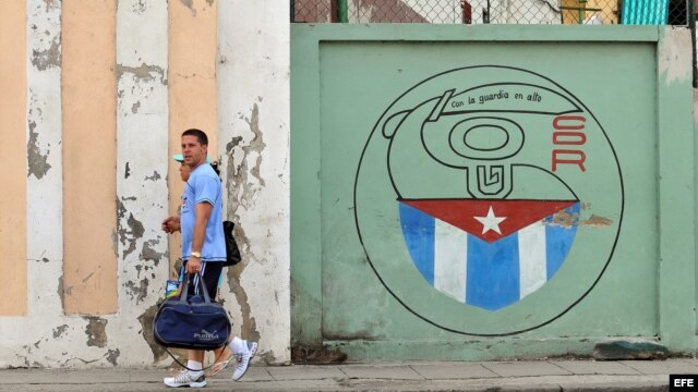 Una pareja camina junto a un cartel con el emblema de los Comités de Defensa de la Revolución (CDR), en La Habana, Cuba.  