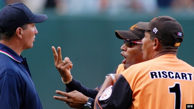 Fotografía de archivo. Víctor Mesa (c) es aguantado por el entrenador de lanzamiento de su equipo, mientras discute con el árbitro principal durante un juego en el estadio Latinoamericano de La Habana, Cuba.