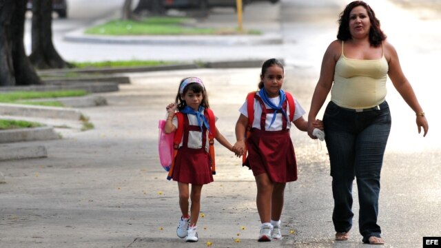 Dos niñas son llevadas por su madre hacia la escuela.
