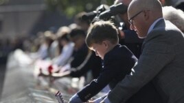 Un niño localiza el nombre de un pariente durante los actos en recuerdo de los fallecidos en los atentados
