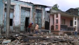 Dos hombres limpian escombros en una casa que ha sido parcialmente destruida por el paso del huracán "Sandy".