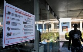 Un hombre pasa junto a un cartel alusivo al control sanitario