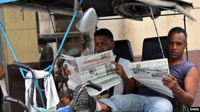 Dos bicitaxistas leen el Granma, en La Habana, Cuba.