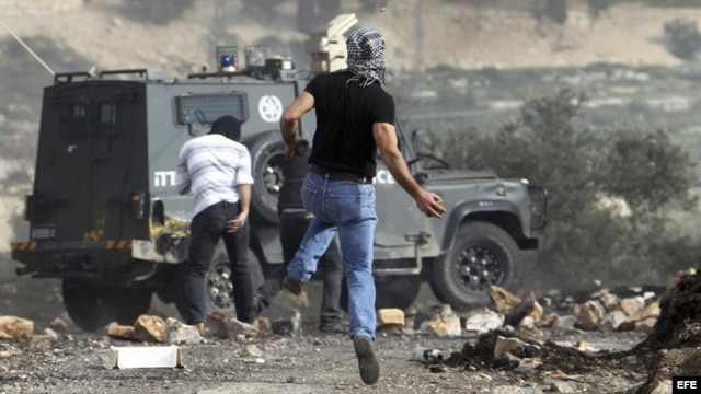 Palestinos lanzan piedras a un vehículo policial israelí durante un protesta contra el asentamiento judío de Kedumim, en Cisjordania.