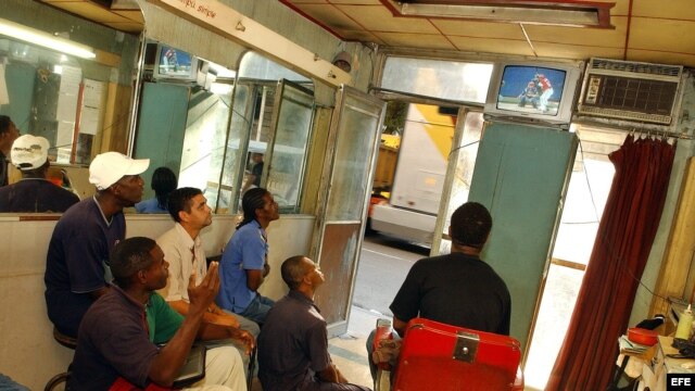 Un grupo de seguidores siguen un evento deportivo en una barbería de La Habana Vieja.